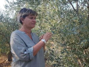 une femme tient dans sa main une branche d'olivier.